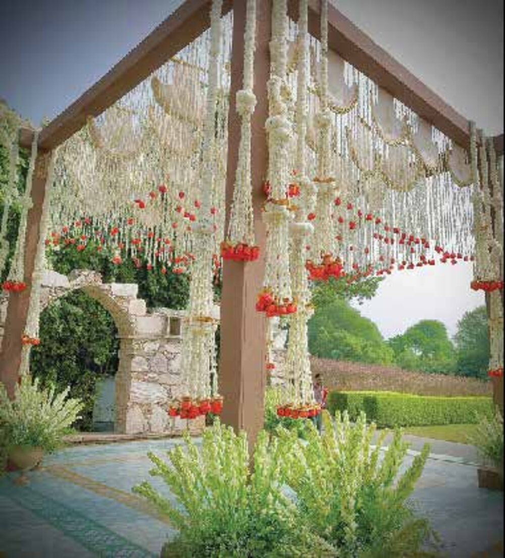 A floral wedding mandap draped in white and red against a Rajasthan fort